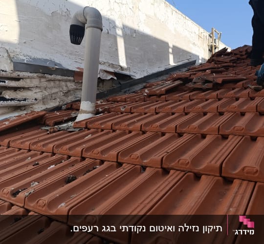 רעפים חומים על גג עם צינור אוורור